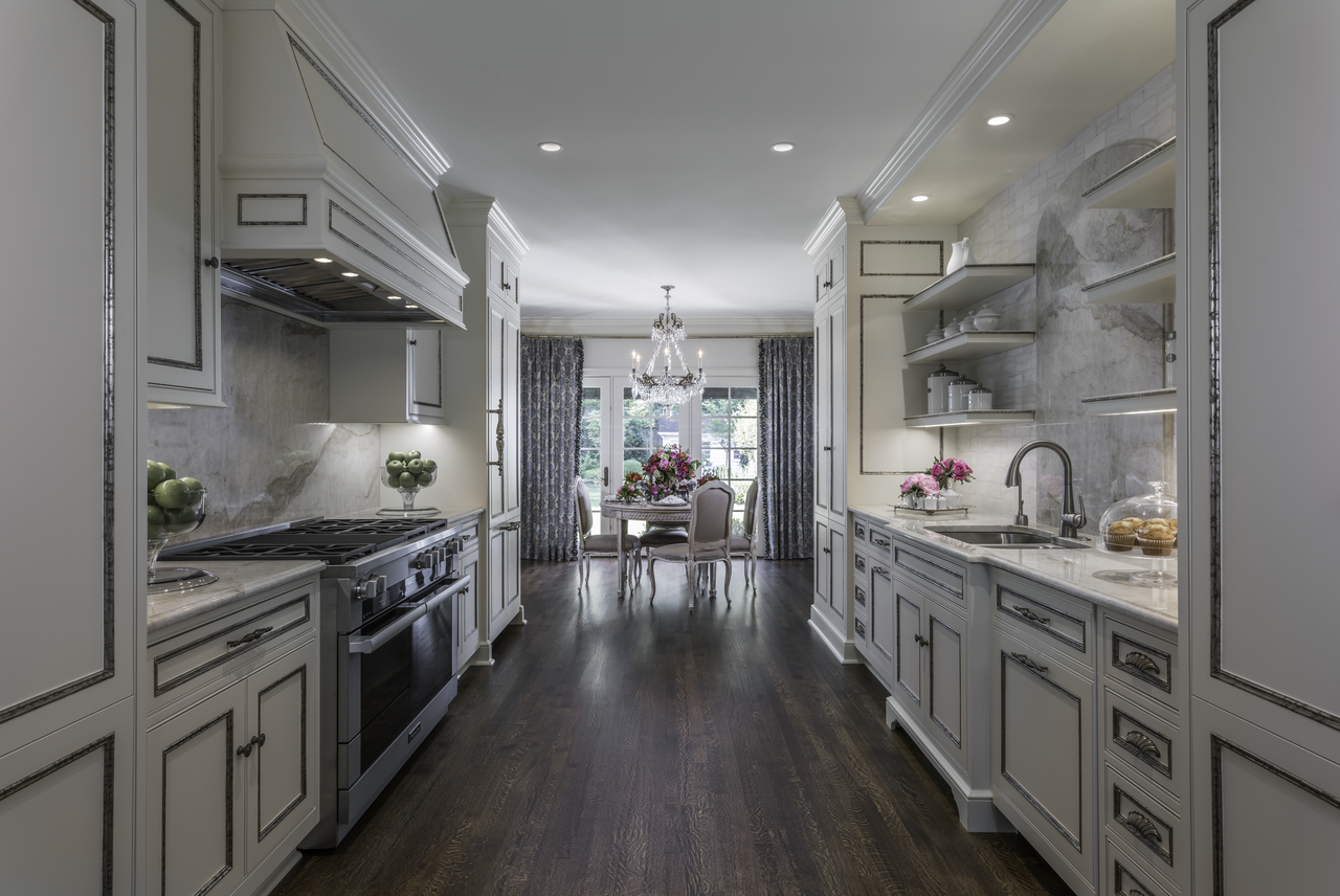 The simple elegance of the white cabinetry and marble counter tops in Ami’s kitchen contrasts exquisitely with the dark-brown, hard-wood flooring. At the far end of the kitchen’s gallery sits her well-appointed tabletop rife with magnificent elements for entertaining friends for brunch. The simple elegance of the white cabinetry and marble counter tops in Ami’s kitchen contrasts exquisitely with the dark-brown, hard-wood flooring. At the far end of the kitchen’s gallery sits her well-appointed tabletop rife with magnificent elements for entertaining friends for brunch.