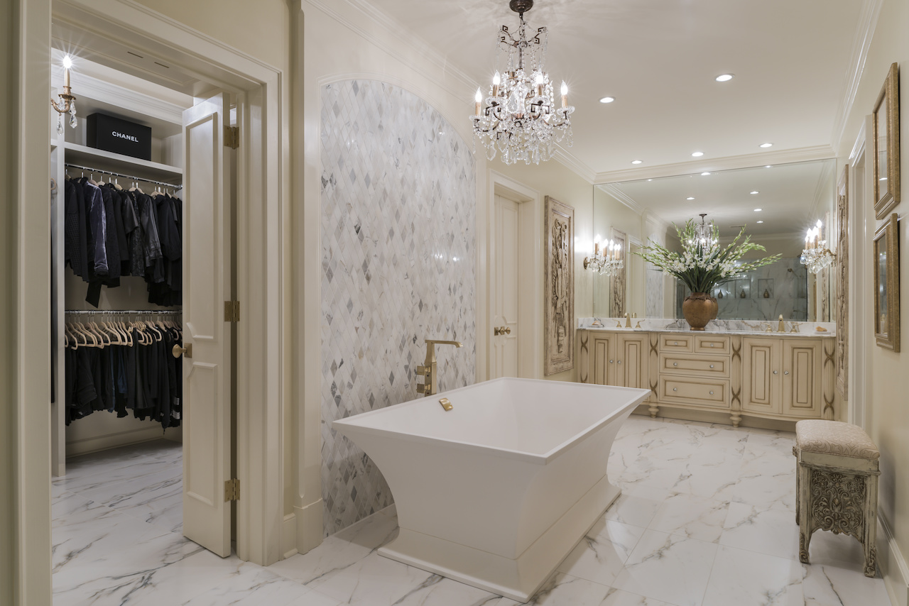 A beautiful Italian chandelier that enhanced and complemented flanking wall sconces, combined with stunning crystal vanity knobs, generates a glamorous atmosphere in this bathroom. Ami used marble and other architectural elements to evoke one single view of the space without separate lines of vision was key, as part of her design plan for the space. A beautiful Italian chandelier that enhanced and complemented flanking wall sconces, combined with stunning crystal vanity knobs, generates a glamorous atmosphere in this bathroom. Ami used marble and other architectural elements to evoke one single view of the space without separate lines of vision was key, as part of her design plan for the space.
