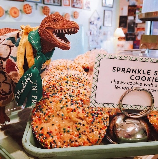 Dino Jeff Goldblum is just one of Muddy's mascots. Image | @muddysbakeshop Dino Jeff Goldblum is just one of Muddy's mascots. Image | @muddysbakeshop