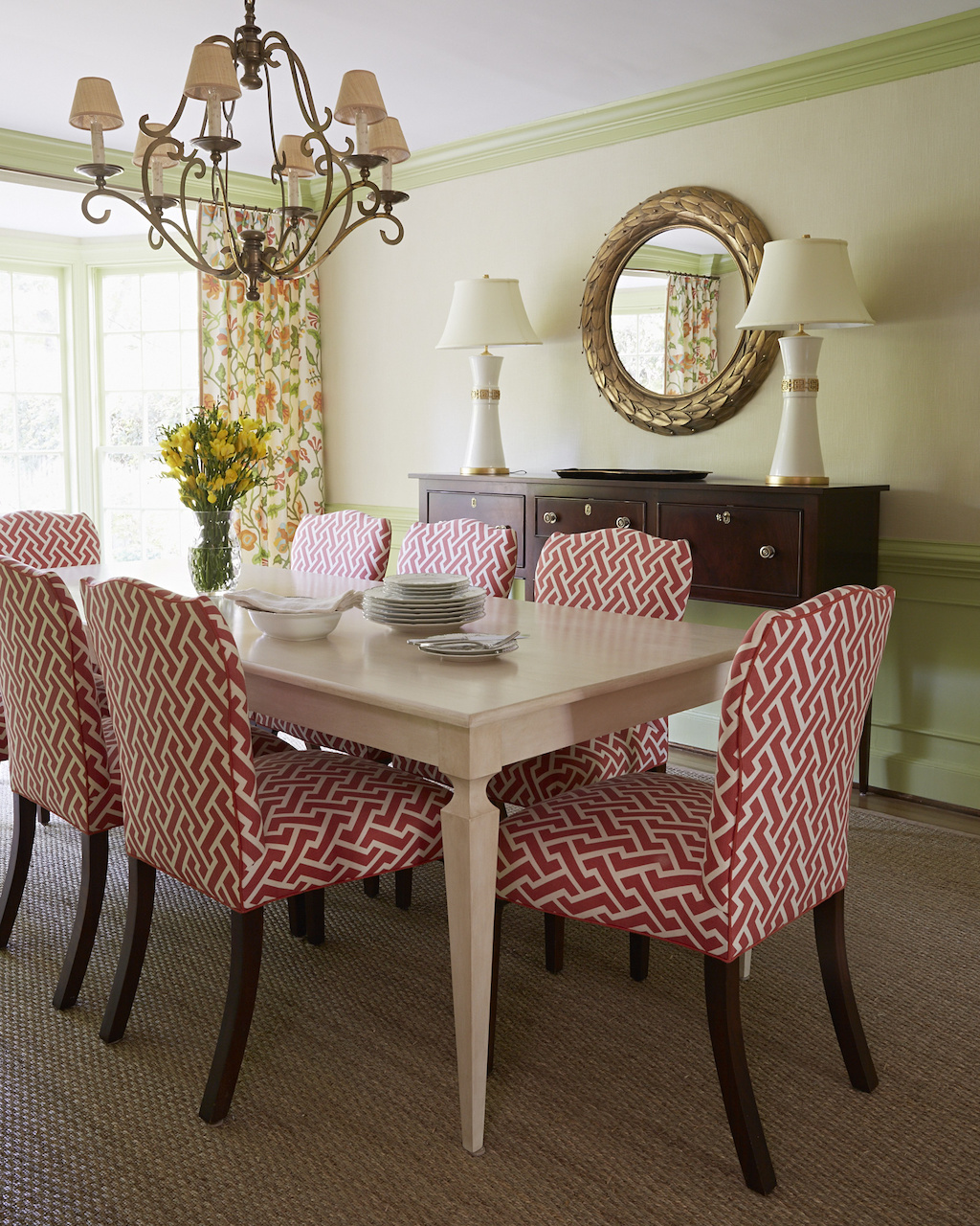 A sideboard by Kittinger and lamps from Mrs. Howard complement the red Quadrille fabric on dining room chairs. A sideboard by Kittinger and lamps from Mrs. Howard complement the red Quadrille fabric on dining room chairs.