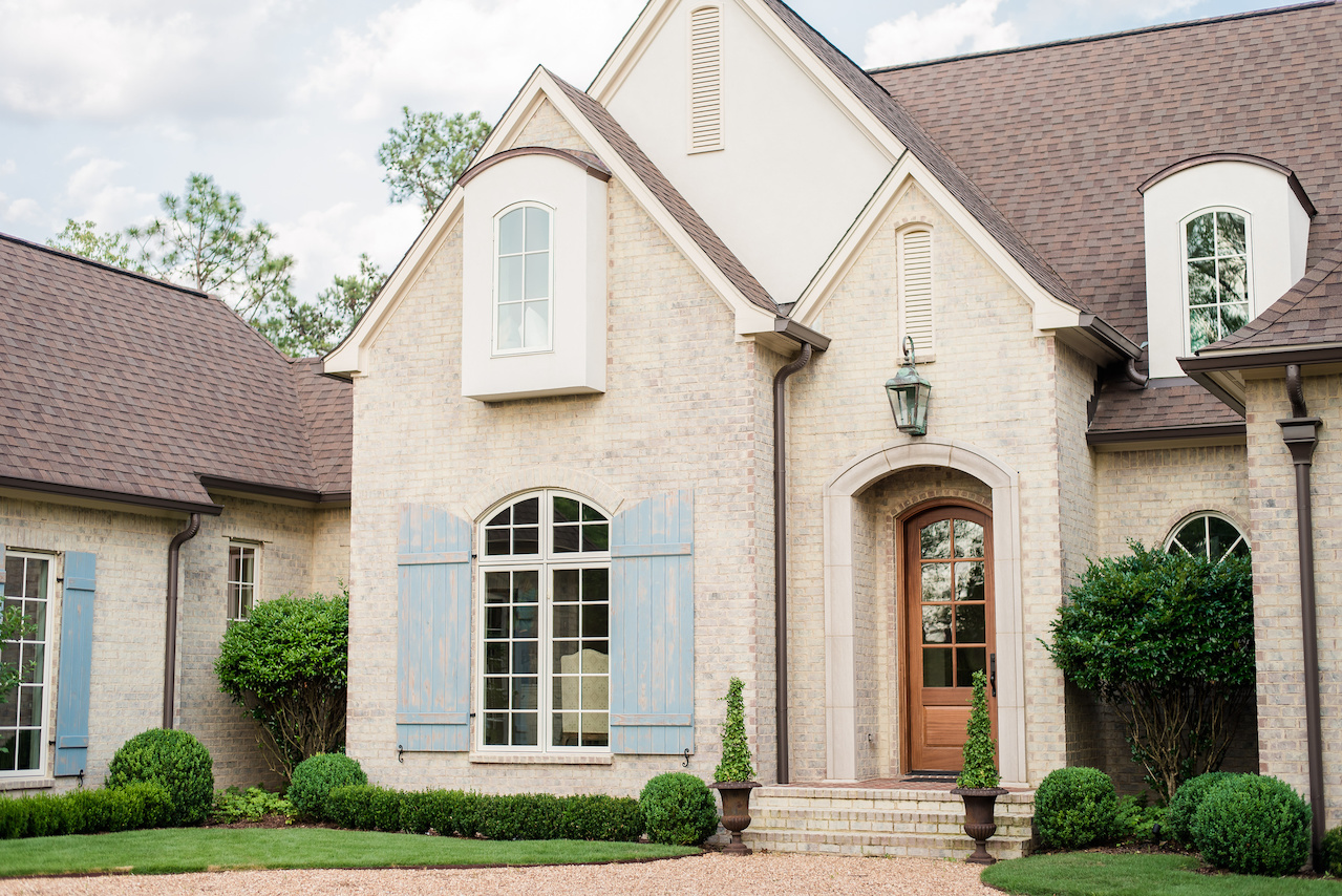 The stately facade of this Modern French Country home is dotted with ivy topiary and boxwoods. The stately facade of this Modern French Country home is dotted with ivy topiary and boxwoods.