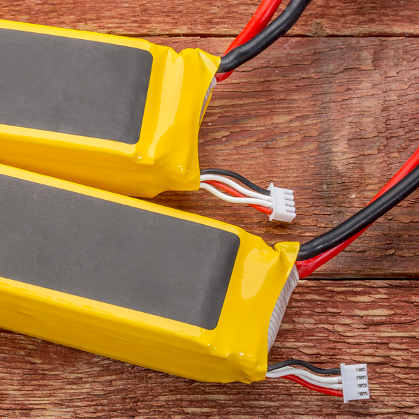 Two rechargeable batteries in yellow and grey protective wrapping sitting on a wooden table