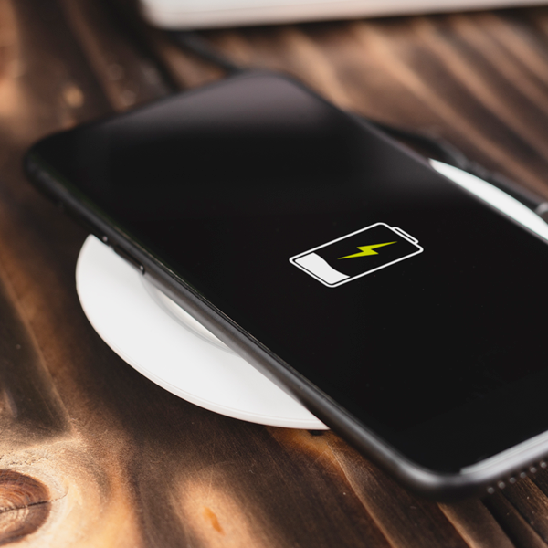 A smartphone charges on a white charging pad