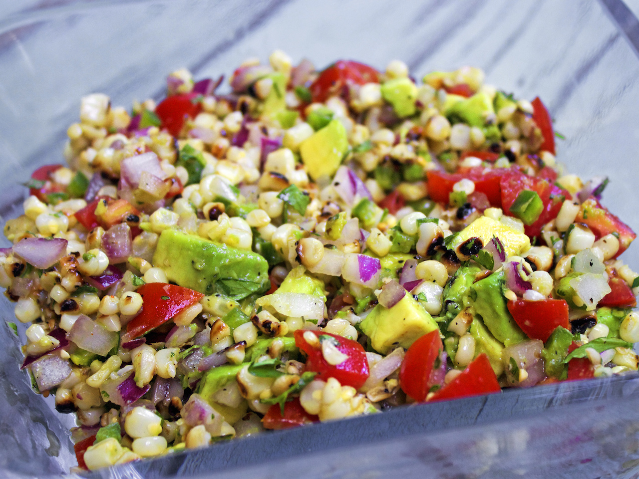 Once you have grilled corn, it's hard to go back to plain. Tomato, corn, avocado and onion salad, done on the grill for maximum taste.