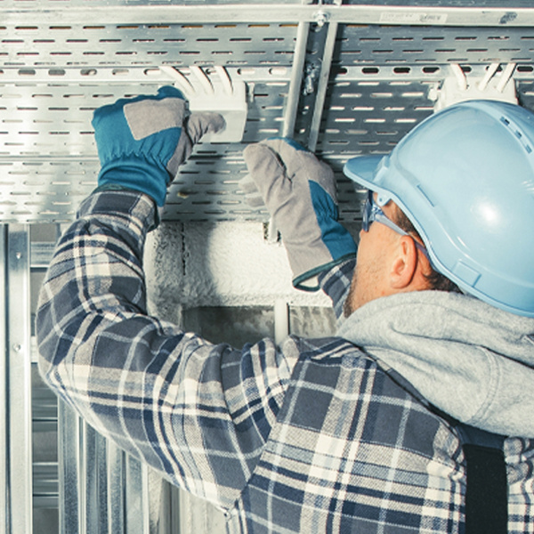 A person installs a sensor on the ceiling of a building