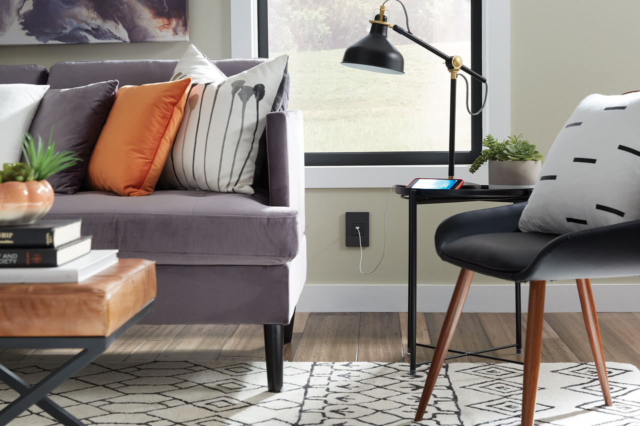 adorne USB Type A/A outlet in graphite with graphite wall plate with graphite wall plate in modern living room with cord plugged in