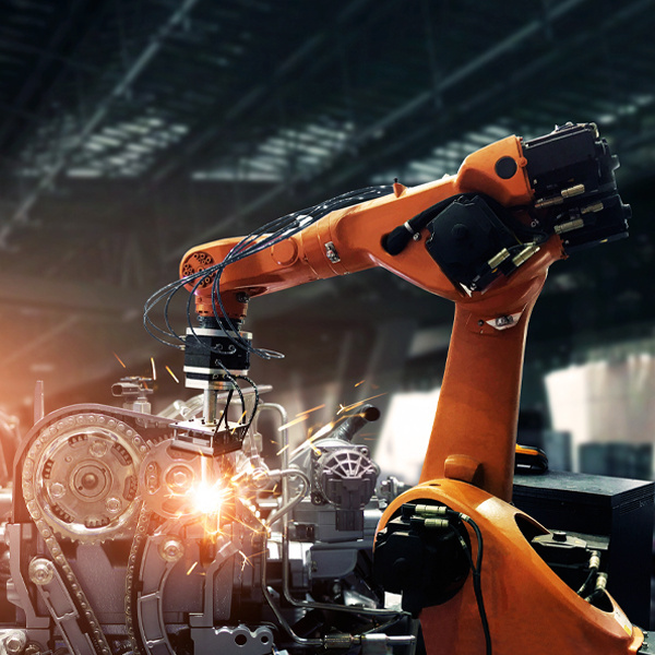 A factory worker seen from behind adjusts their yellow hard hat while checking machine status data on a tablet computer