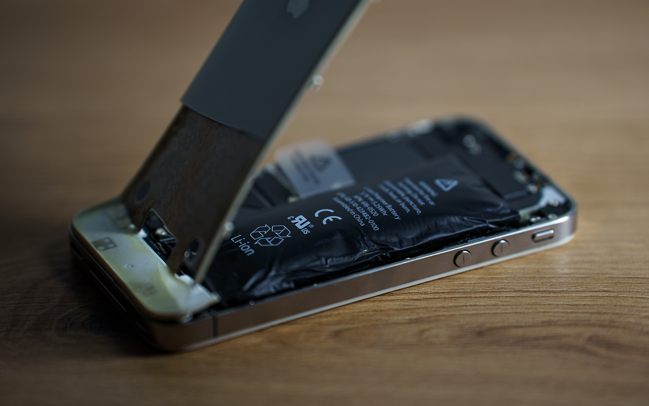 Lors d’une réparation, une batterie est retirée du boîtier ouvert d’un smartphone à l’aide d’un outil