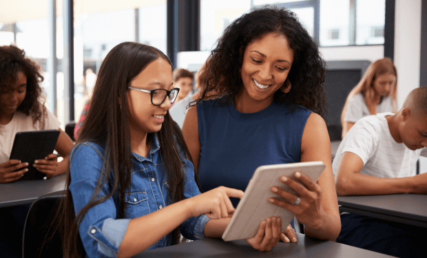 教师在课堂上协助学生一起查看平板电脑