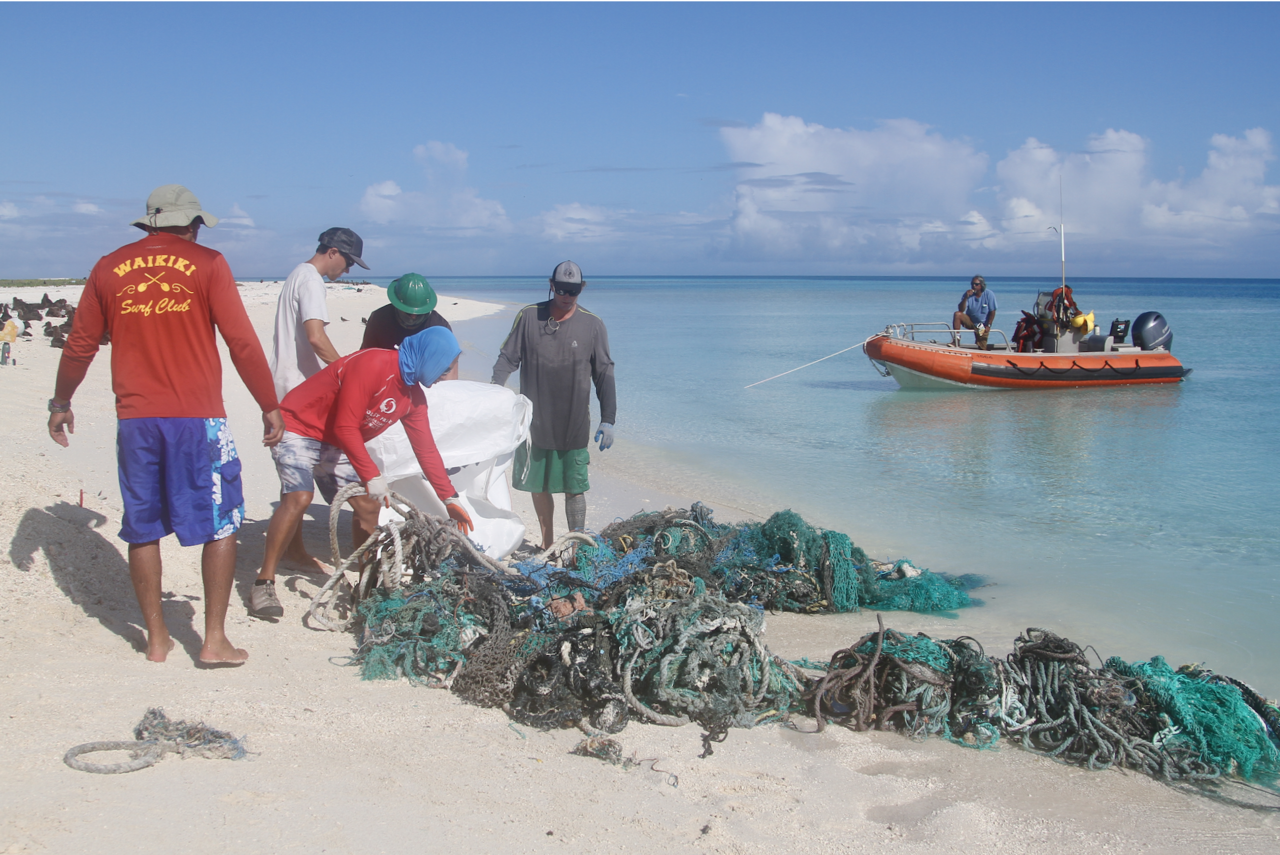 Researchers on beach with derelict fishing net. Boat in background.
