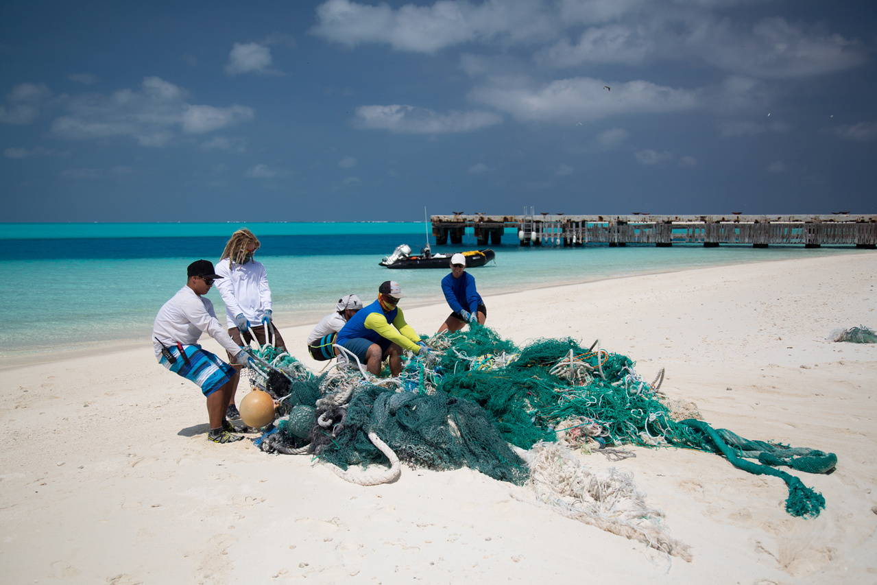The team continued removing debris from the shorelines of Eastern Island on April 16, 2016. The team members hauled a large net conglomerate into a small boat. Photo: NOAA Fisheries/Ryan Tabata