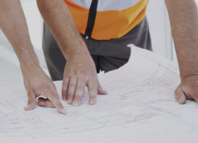 construction worker pointing at blueprints