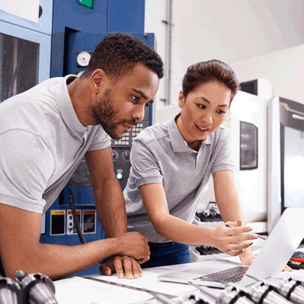 Two people in grey shirts looking at a grey lap top computer