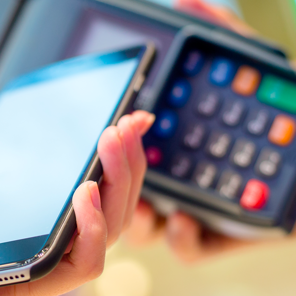 A person pays by tapping their smartphone on a card reader