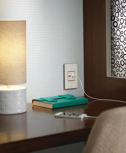 adorne mirror white wall plate installed above hotel nightstand with USB charging cord plugged in