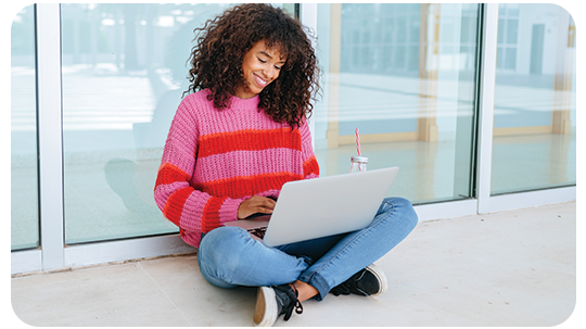 Woman sitting on ground using laptop